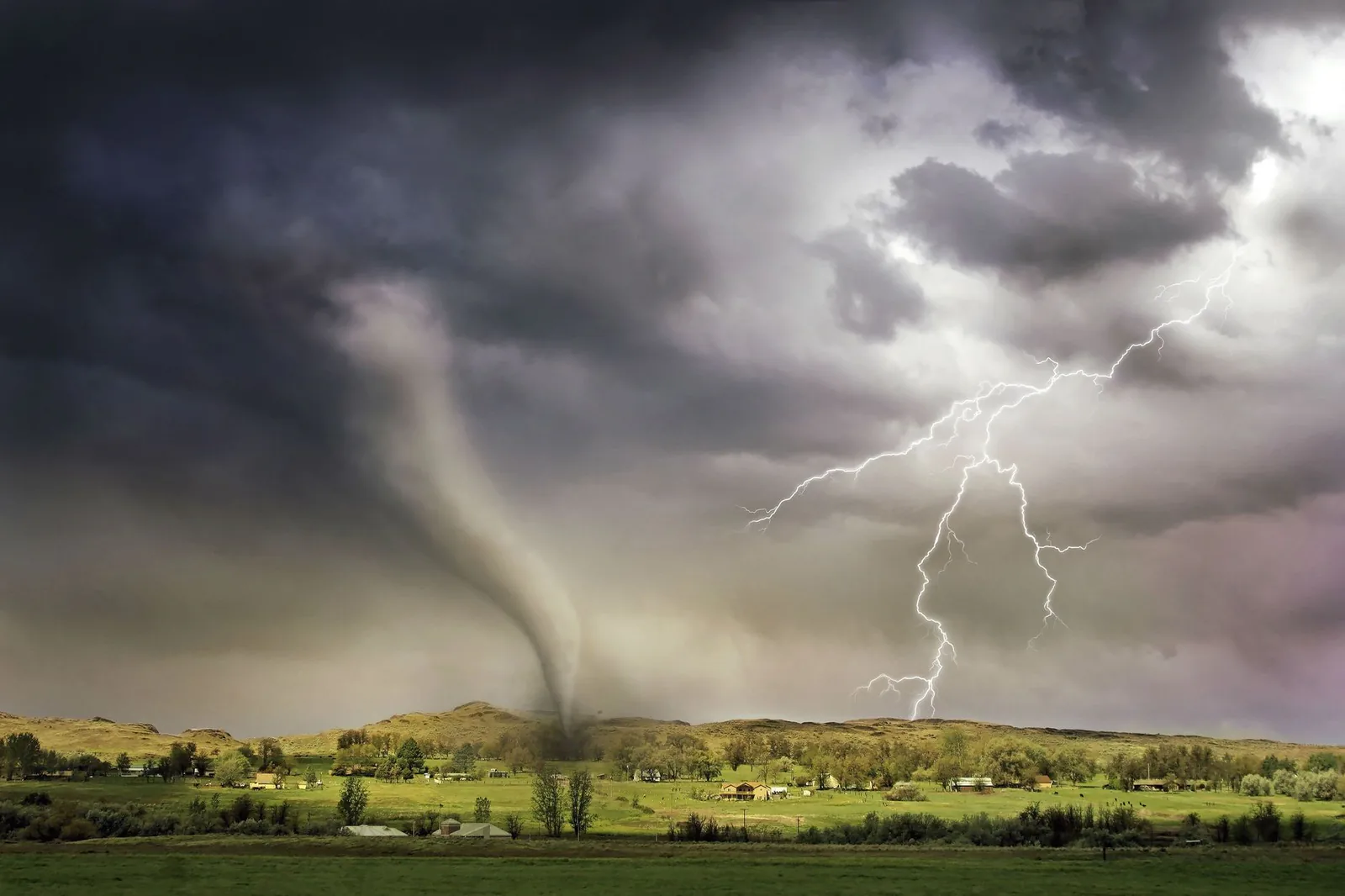 A tornado and lightning over a dark countryside landscape
