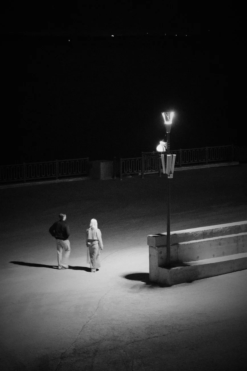 A couple walking apart under streetlights at night