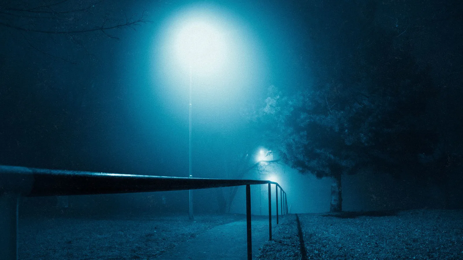 Streetlights glowing through dense night fog