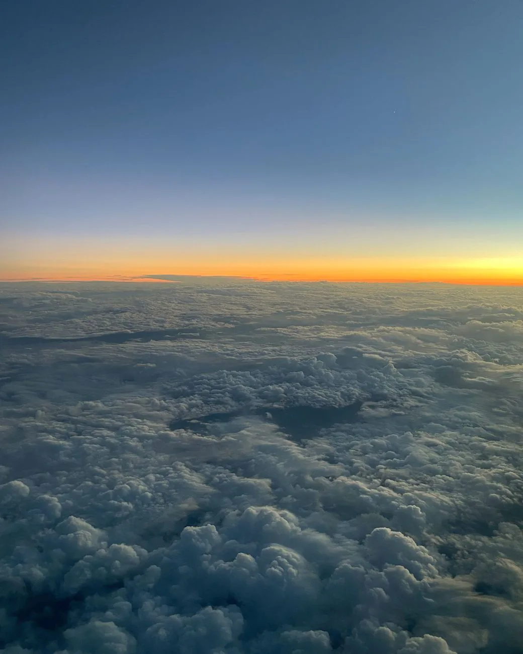 Clouds seen from above at twilight with a glowing horizon